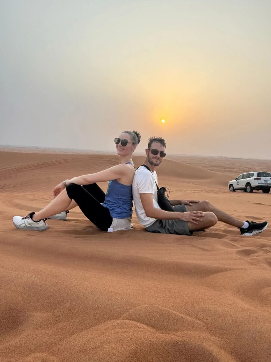 Couple sitting back to back watching sunset in the desert